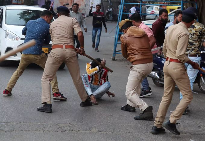 Indische Polizisten schlagen in Ahmadabad mit Schlagstöcken auf einen Mann bei Protesten ein. Indien