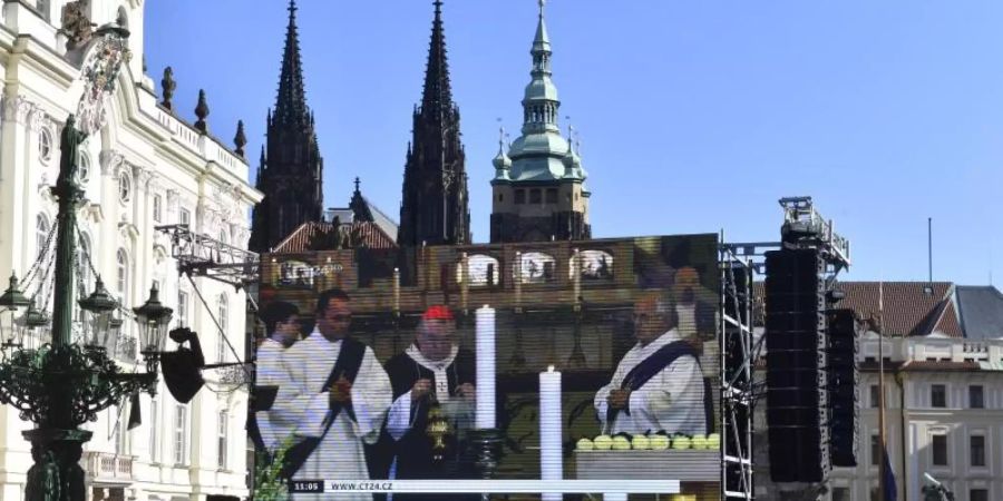 Fans stehen auf dem Hradschiner Platz und schauen auf einen Grossbildschirm, auf dem die Trauerfeier für den Sänger Karel Gott im Prager Veitsdom übertragen wird. F. Foto: Vít imánek/CTK/dpa