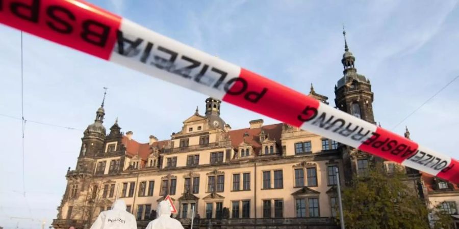 Zwei Mitarbeiter der Spurensicherung stehen vor dem Residenzschloss mit dem Grünen Gewölbe hinter einem Absperrband. Foto: Sebastian Kahnert/dpa-Zentralbild/dpa