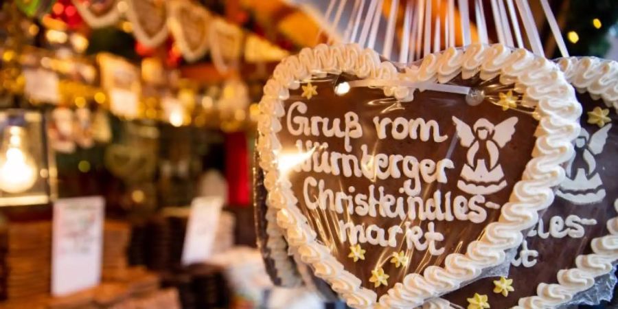 Lebkuchenherzen mit der Aufschrift «Gruss vom Nürnberger Christkindlesmarkt» hängen an einem Stand auf dem Nürnberger Christkindlesmarkt. Foto: Daniel Karmann/dpa