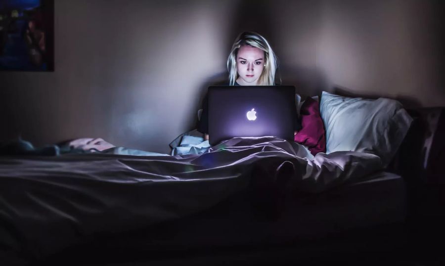 junge Frau vor Laptop im Bett nachts