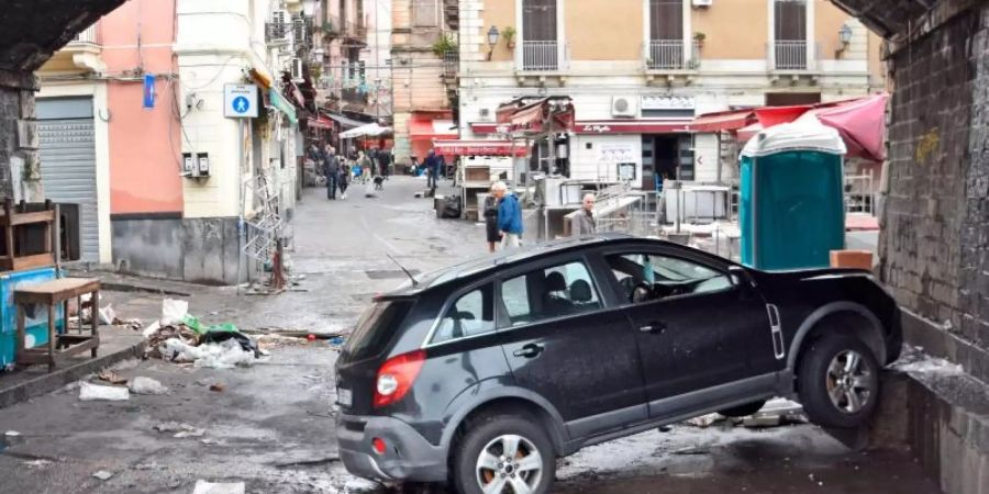 Ein Auto steckt, einen Tag nachdem Sizilien von einem heftigen Unwetter mit Überschwemmungen heimgesucht wurde, unter einer Unterführung an einer Mauer fest. Foto: Andrea Di Grazia/LaPresse/AP/dpa