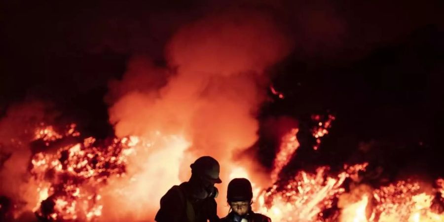 Wissenschaftler führen geophysikalische Messungen durch, während Lava aus einem Vulkan ins Meer fliesst. Nun ist ein Mann im Zusammenhang mit dem Vulkanausbruch ums Leben gekommen. Foto: Taner Orribo/AP/dpa