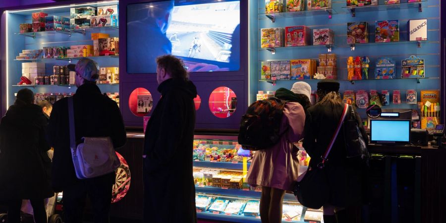 Besucher der Spielhalle «Gamestate» am Potsdamer Platz stehen an einem Tresen an.