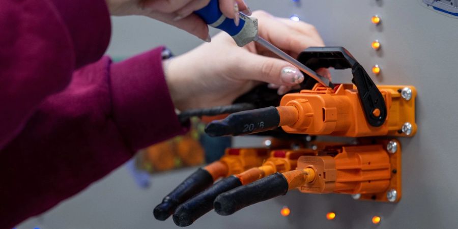 Eine angehende KfZ-Mechatronikerin überprüft im Volkswagen Bildungsinstitut in Zwickau Stecker für ein Ladegerät.