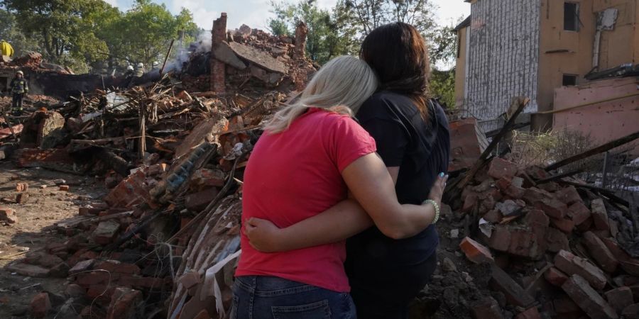 Ukrainische Frauen stehen vor den Trümmern eines Hauses in Charkiw, das bei einem Raketenangriff zerstört wurde.