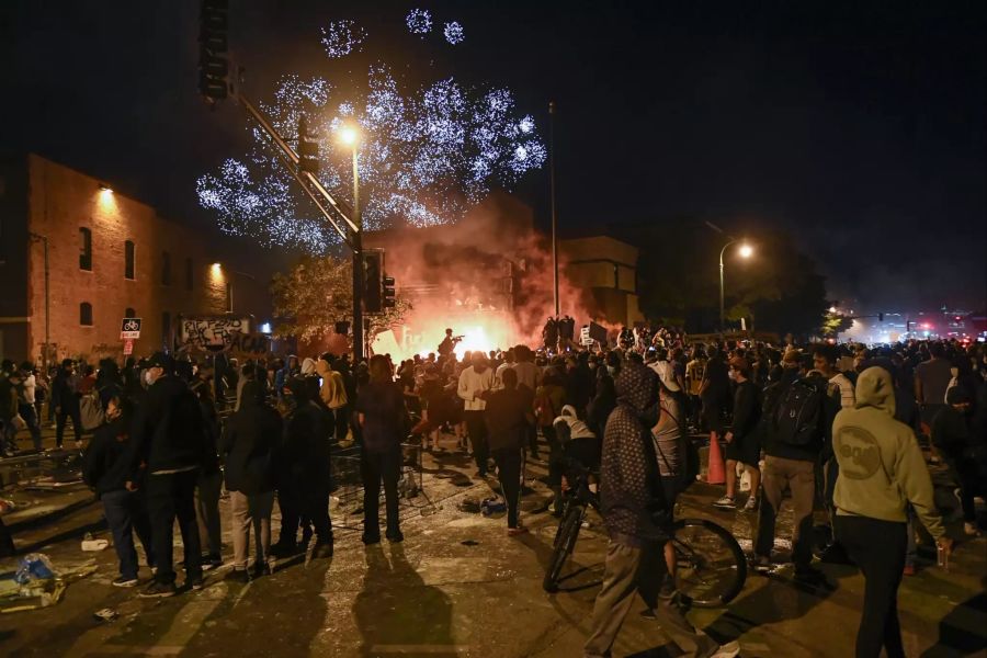 Demonstranten jubeln, als Feuerwerkskörper angezündet werden und in der Nähe eines verlassenen Polizeireviers mehrere Feuer brennen.