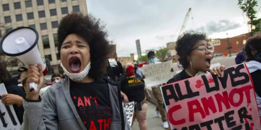 Shayana Dabney (l.) führt während eines Protestes in Colorado Springs eine Gruppe von Demonstranten mit einem Megafon durch die Innenstadt. Foto: Christian Murdock/The Gazette/AP/dpa