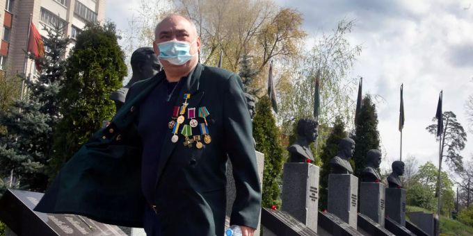 Ein Veteran mit Mundschutz besucht eine Gedenkstätte für die Opfer der Nuklearkatastrophe von Tschernobyl. Nuklearkatastrophe von Tschernobyl
