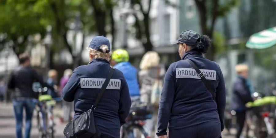 Zwei Mitarbeiterinnen vom Ordnungsamt kontrollieren die Marktstände in der Berliner Strasse in der Innenstadt von Gütersloh. Foto: David Inderlied/dpa