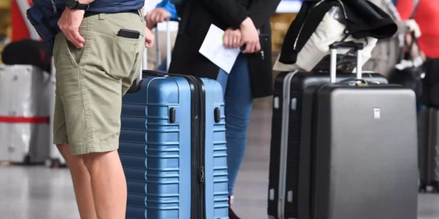 Flugreisende stehen in Terminal 1 des Frankfurter Flughafens am Check-in-Schalter an. Reiserückkehrer aus Risikogebieten sollen sich an Flughäfen verpflichtend auf das Coronavirus testen lassen. Foto: Arne Dedert/dpa