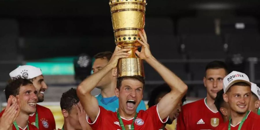 Münchens Thomas Müller hält die Trophäe nach dem Spiel hoch. Foto: Alexander Hassenstein/Getty Images Europe/Pool/dpa