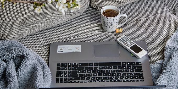 Das Homeoffice auf dem Sofa lässt sich auch geniessen. Laptop Decke Sofa Kaffee Blüte Fernsehbedienung