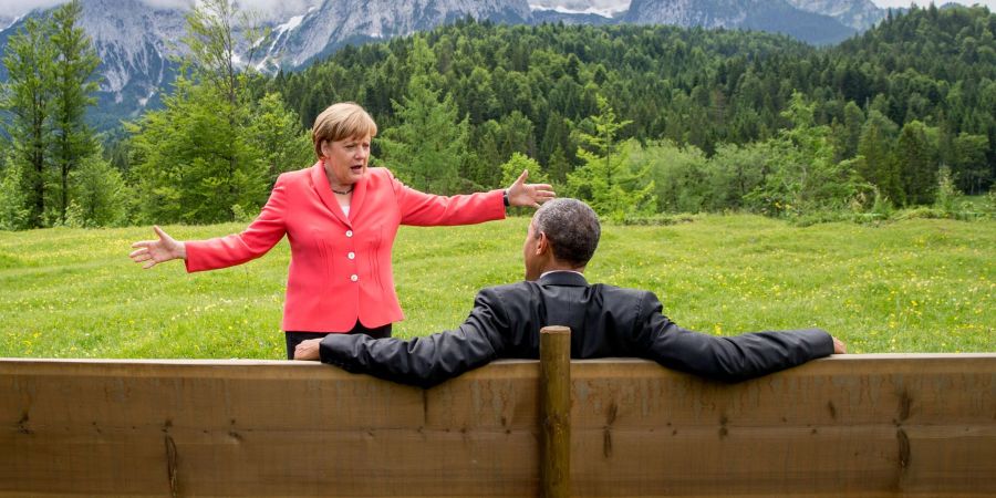 Die damalige Bundeskanzlerin Angela Merkel (CDU) spricht mit dem damaligen US-Präsidenten Barack Obama bei der G7-Konferenz 2015 auf einer Wiese bei Schloss Elmau vor der Wettersteinspitze.