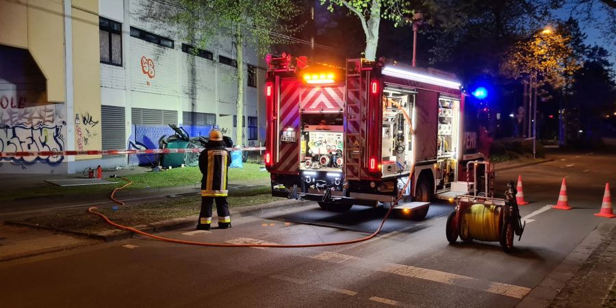 Ein Feuerwehrmann steht neben dem Wrack eines Autos, in dem zwei junge Männer aus der obersten Etage eines Parkhauses gestürzt und ums Leben gekommen sind.