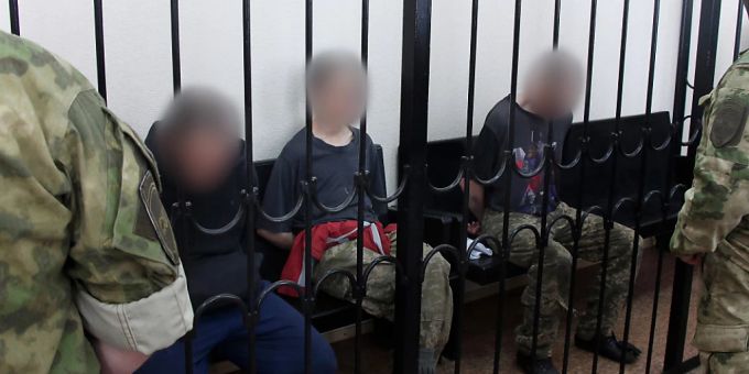 Zwei britische Staatsbürger (links und rechts) sowie ein marokkanischer Staatsbürger sitzen hinter Gittern in einem Gerichtssaal in Donezk. Foto: Uncredited/AP/dpa - ACHTUNG: Personen wurden aus rechtlichen Gründen gepixelt Zwei britische Staatsbürger (links und rechts) sowie ein marokkanischer Staatsbürger sitzen hinter Gittern in einem Gerichtssaal in Donezk. Foto: Uncredited/AP/dpa - ACHTUNG: Personen wurden aus rechtlichen Gründen gepixelt