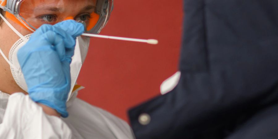 Ein Mitarbeiter nimmt einen Abstrich von einer Patientin für einen PCR-Test.