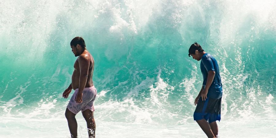 Zwei Männer vor einer hohen Brandung in Waikiki. Massive Wellen trafen an der Südküste Hawaiis auf Land.