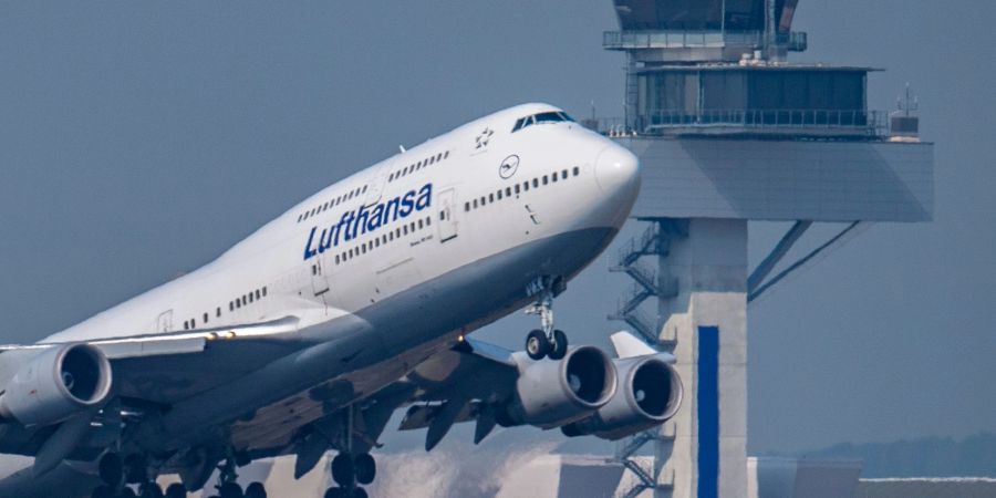 Eine Passagiermaschine vom Typ Boeing 747 der Lufthansa startet vor dem Tower des Flughafens Frankfurt zu einem Transatlantikflug.