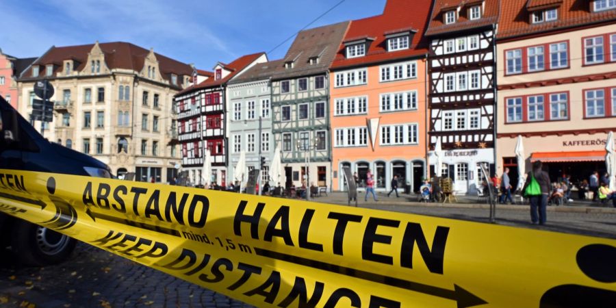 «Abstand halten!» steht in deutscher und englischer Sprache auf einem Flatterband am Domplatz inmitten der Altstadt von Erfurt.