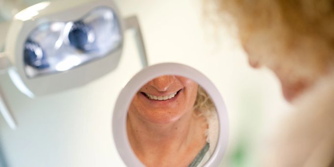 Auch künstliche Zähne können von Zahnstein befallen sein. Frau Gebiss Spiegel Zahnarzt Prothese