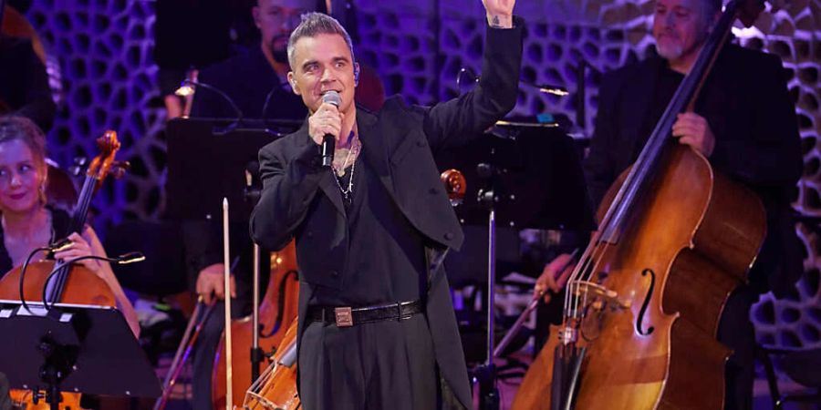 Anlässlich des 25. Jubiläums seiner Solo-Karriere gab Robbie Williams, britischer Sänger und Songwriter, zusammen mit dem Orchester der Neuen Philharmonie Frankfurt in der Elbphilharmonie ein mitreissendes Konzert. Foto: Georg Wendt/dpa - ACHTUNG: Nur zur redaktionellen Verwendung im Zusammenhang mit der aktuellen Berichterstattung über das Konzert in der Elbphilharmonie und nur mit vollständiger Nennung des vorstehenden Credits. Keine Verwendung nach dem 29.11.2022!!