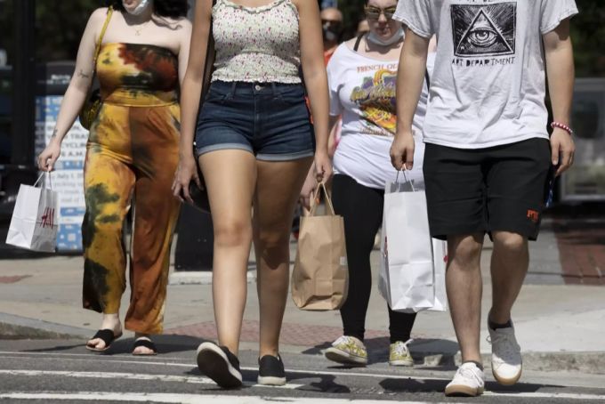 Menschen überqueren mit Einkaufstaschen und Schutzmasken eine Strasse in Boston (USA). Wirtschaft