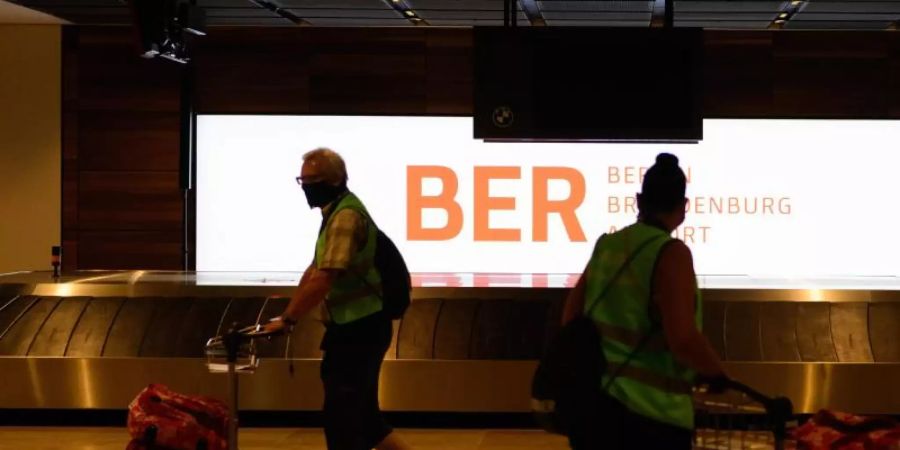 Komparsen in Warnwesten gehen beim Probelauf im Terminal 1 des Hauptstadtflughafens Berlin-Brandenburg (BER) mit ihren Koffern zum Check in. Foto: Soeren Stache/dpa-Zentralbild/dpa