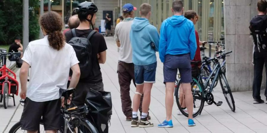 Kunden einer Fahrradwerkstatt stehen vor der Tür des Geschäftes in einer Schlange an. Foto: Sebastian Willnow/dpa-Zentralbild/dpa
