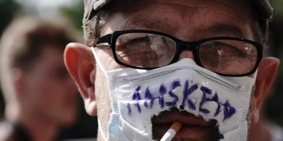 «Masken Weg!» steht auf dem «Mundschutz» eines Teilnehmers einer Demonstration gegen die Corona-Massnahmen. Künftig wird es zur Pflicht, auf Demonstrationen in Berlin Masken zu tragen. Foto: Michael Kappeler/dpa
