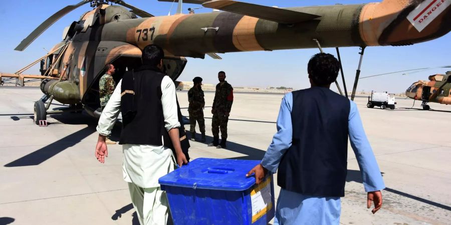 Mitarbeiter der Afghanischen Unabhängigen Wahlkommission tragen eine Kiste mit Wahlmaterial zu einem Hubschrauber auf einem Flughafen in der Provinz Kandahar.