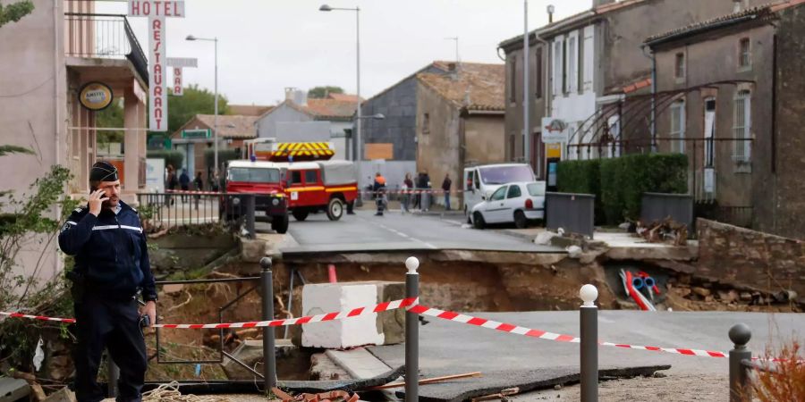 Ein französischer Polizist steht bei einer zerstörten Strasse nach den Unwettern in Südfrankreich.