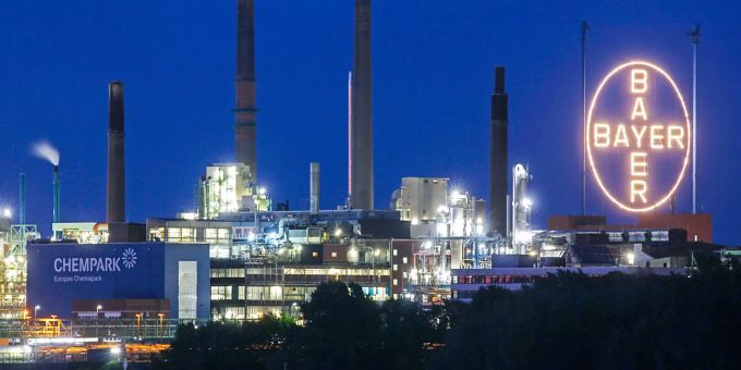 Bayer kündigte einen Mega-Abbau bis 2021 an. Das Bayer-Kreuz leuchtet auf dem Werksgelände.
