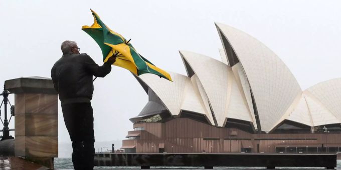 Ein Mann geht am Sydney Opera House bei Regen vorbei. Ein Mann geht am Sydney Opera House bei Regen vorbei.