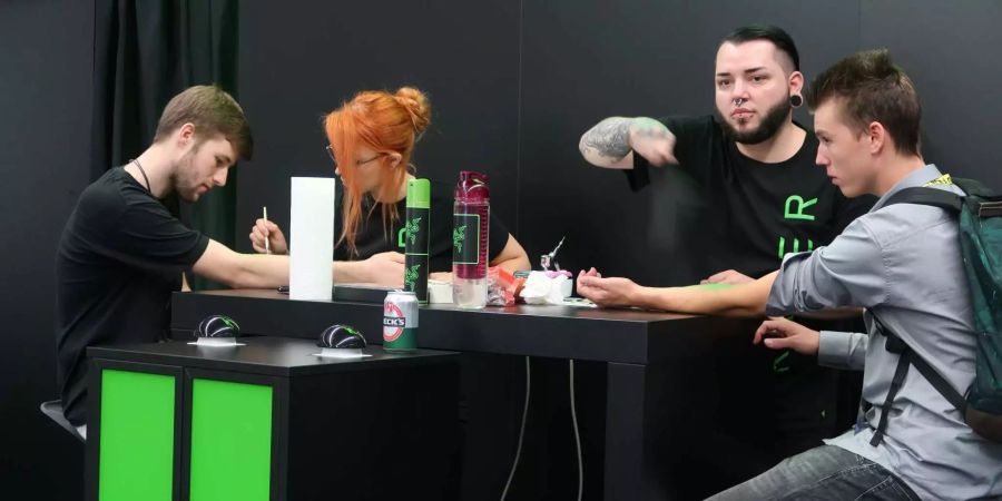 Viele versuchten zudem, Besucher mit speziellen Aktionen an ihre Stände zu locken, wie hier beispielsweise Razer. Zwei Besucher lassen sich gerade den Unterarm mit dem Razer-Logo bemalen.