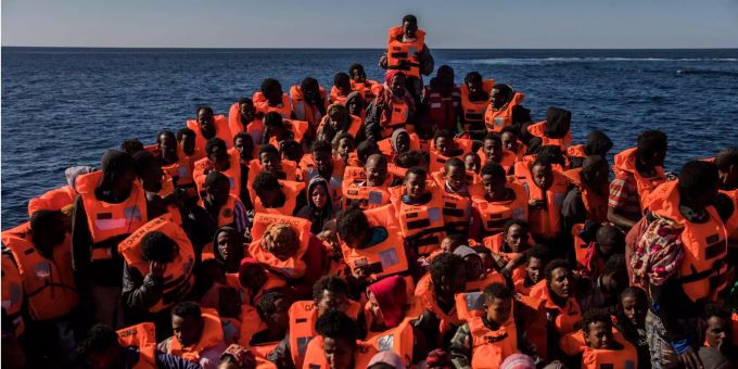 Mehrere Flüchtlinge aus verschiedenen afrikanischen Ländern sitzen vor der Küste von Libyen an Bord eines überfüllten Holzbootes. Mehrere Flüchtlinge aus verschiedenen afrikanischen Ländern sitzen vor der Küste von Libyen an Bord eines überfüllten Holzbootes.