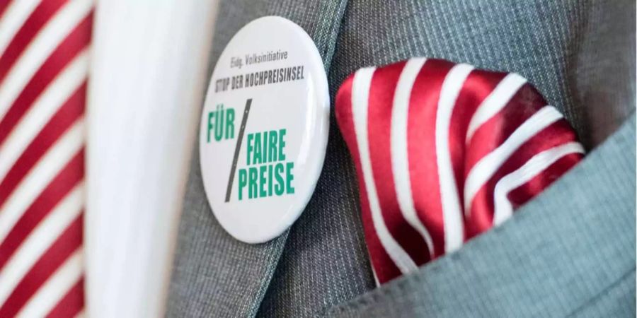 Ein Button der Fair-Preis-Initiative – Eidg. Volksinitiative, Stop der Hochpreisinsel, für faire Preise – am Revers eines grauen Anzugs.