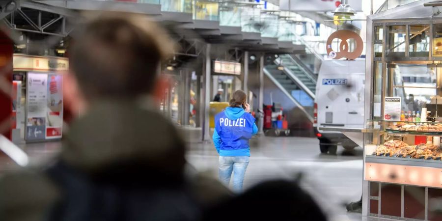 Eine Polizistin ist hinter einem Absperrgitter im Hauptbahnhof München zu sehen.