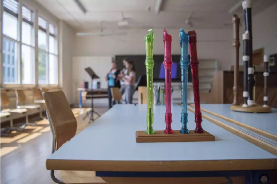 Blockflöten einer Schule und im Hintergrund sind Schüler am Üben - Keystone