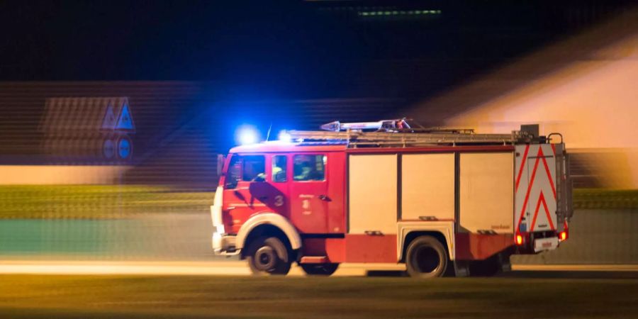 Ein Feuerwehrauto mit Sirene fährt die Strasse entlang.