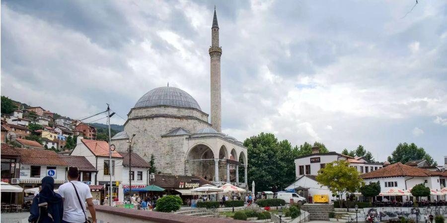 Vor der Sinan-Pascha-Moschee in Prizren laufen zwei Menschen über eine Brücke.