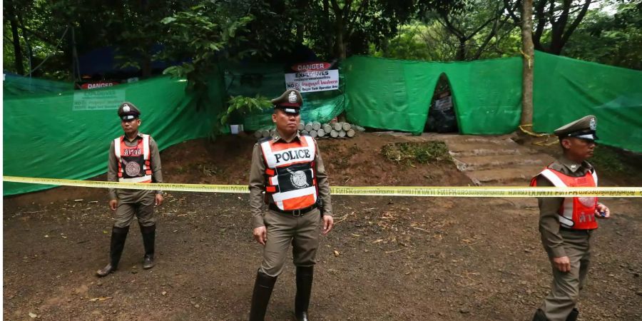 Polizisten bewachen den abgesperrten Zugang zu der Höhle.