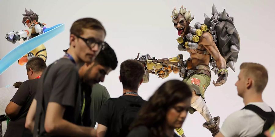 Köln: Besucher der Gamescom warten vor Figuren aus dem Spiel Overwatch von Blizzard Entertainment.