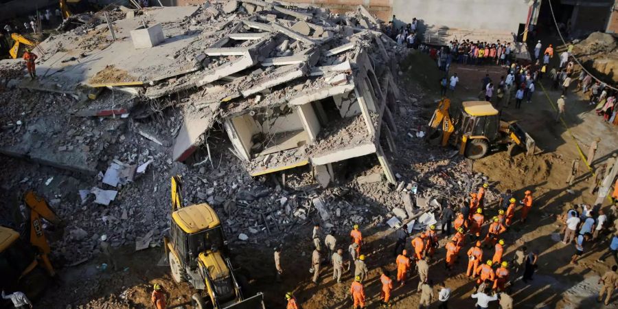 Rettungskräfte suchen nach dem Gebäudeeinsturz in der Nähe von Neu-Dehli nach Verletzten.