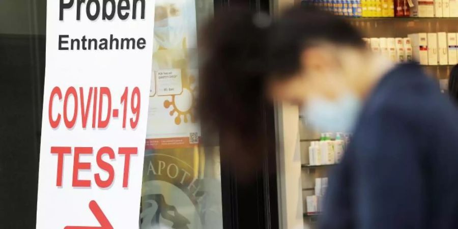 Eine Frau füllt vor einer Apotheke in Bonn ein Formular für einen Covid-19-Test aus. Foto: Oliver Berg/dpa