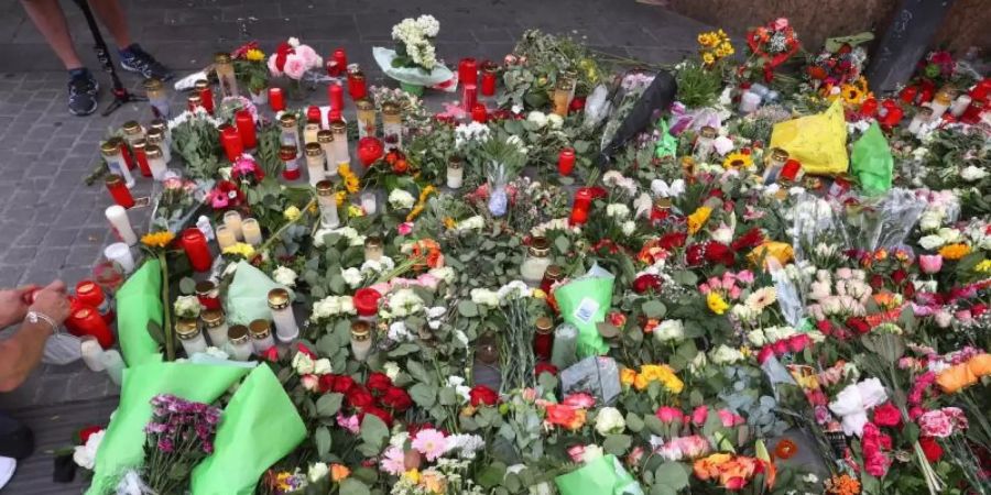 Ein Mann entzündet vor einem geschlossenen und abgesperrten Kaufhaus in der Innenstadt eine Kerze. Foto: Karl-Josef Hildenbrand/dpa