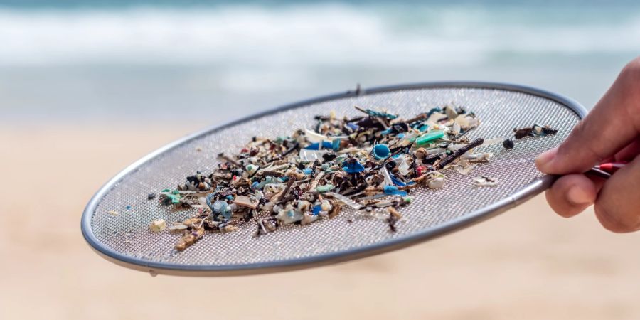 Plastikverschmutzung, Mikroplastik in Meerwasser und Sand gemischt.