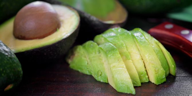 avocado, geschnitten, dunkles schneidebrett