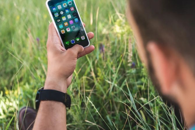 Männlicher Smartphone-User im Gras