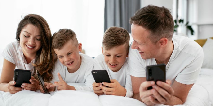 Eltern und Kinder gemeinsam an je einem Smartphone.